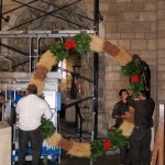 Preparing to hang the wreath in the Romanesque Hall.
